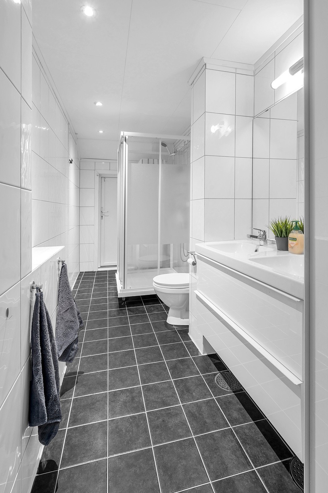 Baderom med fliser på gulv og vegger - dobbel servant, toalett, opplegg for vaskemaskin og dusj Galleribilde