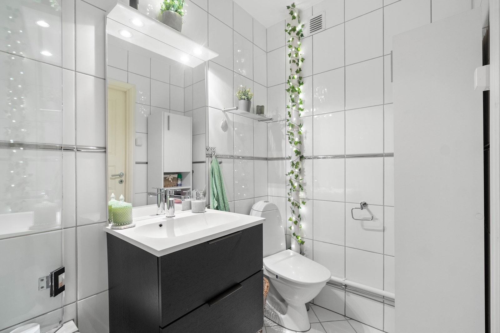 Badet er innredet med toalett, servant med underskuffer og badekar med glassvegg. Galleribilde