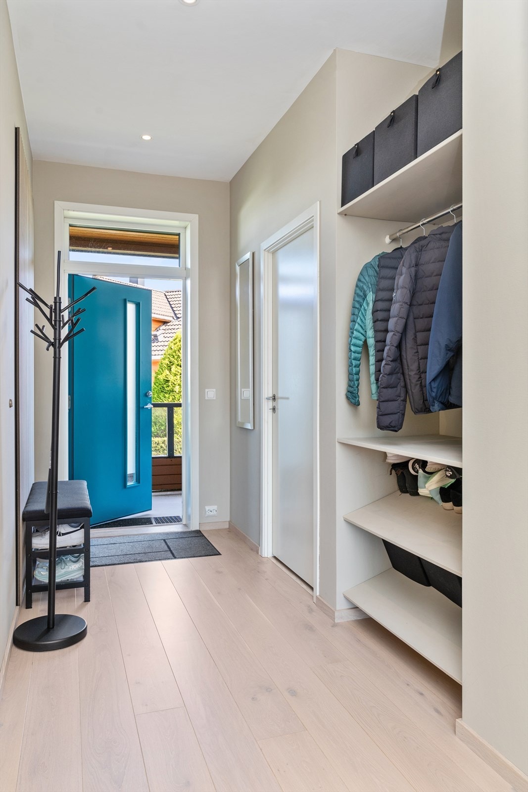 En åpen garderobeløsning i gangen gir praktisk oppbevaring for yttertøy og sko Galleribilde