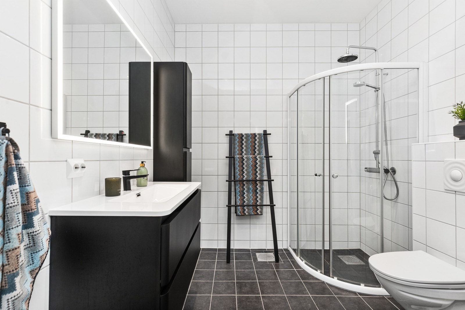 Badet er helfliset og utstyrt med dusjhjørne, vegghengt toalett og servantinnredning Galleribilde