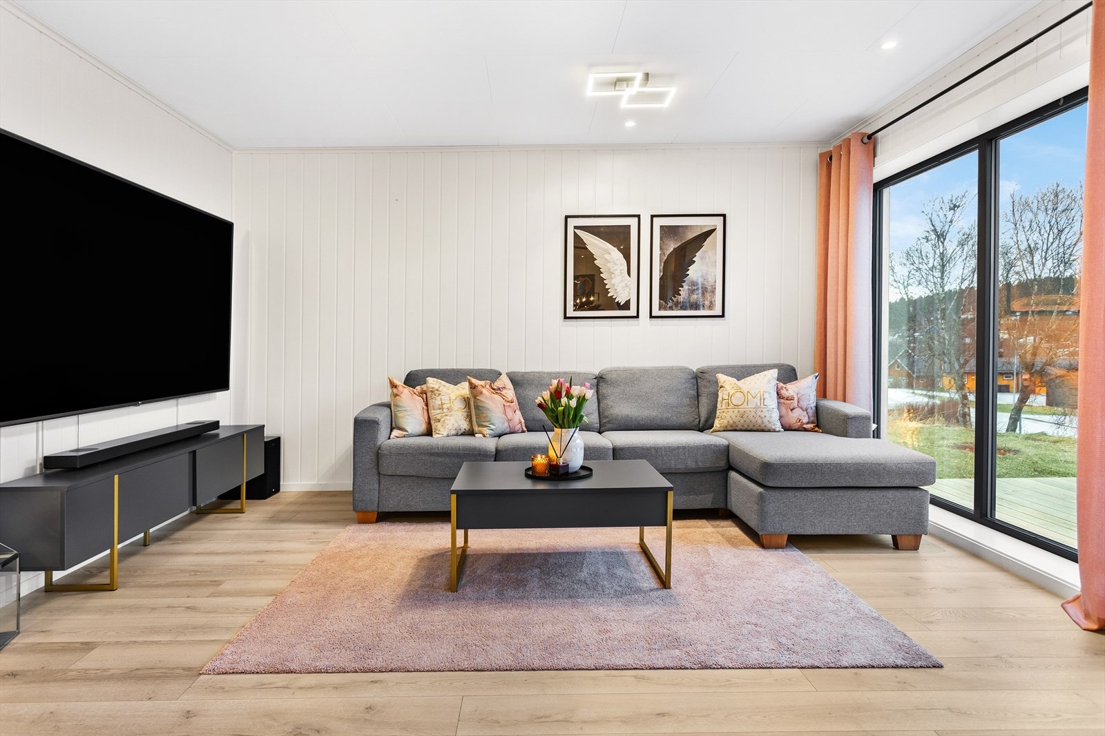 Stue med enstavs laminatgulv, lyse overflater og vegg med plass til romslig TV Galleribilde