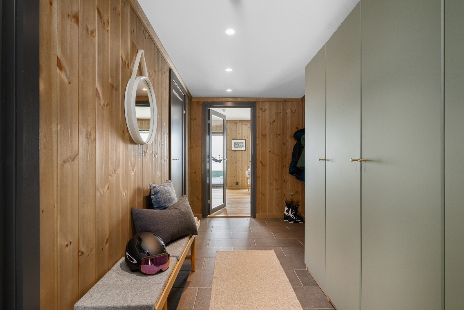 Du ønskes velkommen inn i en stor entré med et pent flislagt gulv og panel på veggene. Allerede her får du en god følelse av den fine standarden. Det er etablert stor garderobe i en pen grønnfarge, noe som gir deg god plass til oppbevaring av klær og sko. Galleribilde