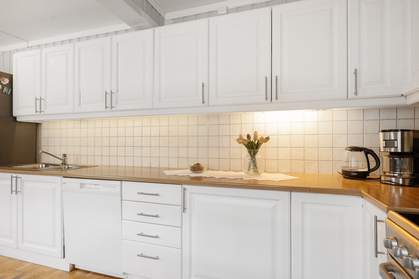 Over benk er det lagt klassiske, lyse fliser. Hvitevarer er frittstående. Galleribilde