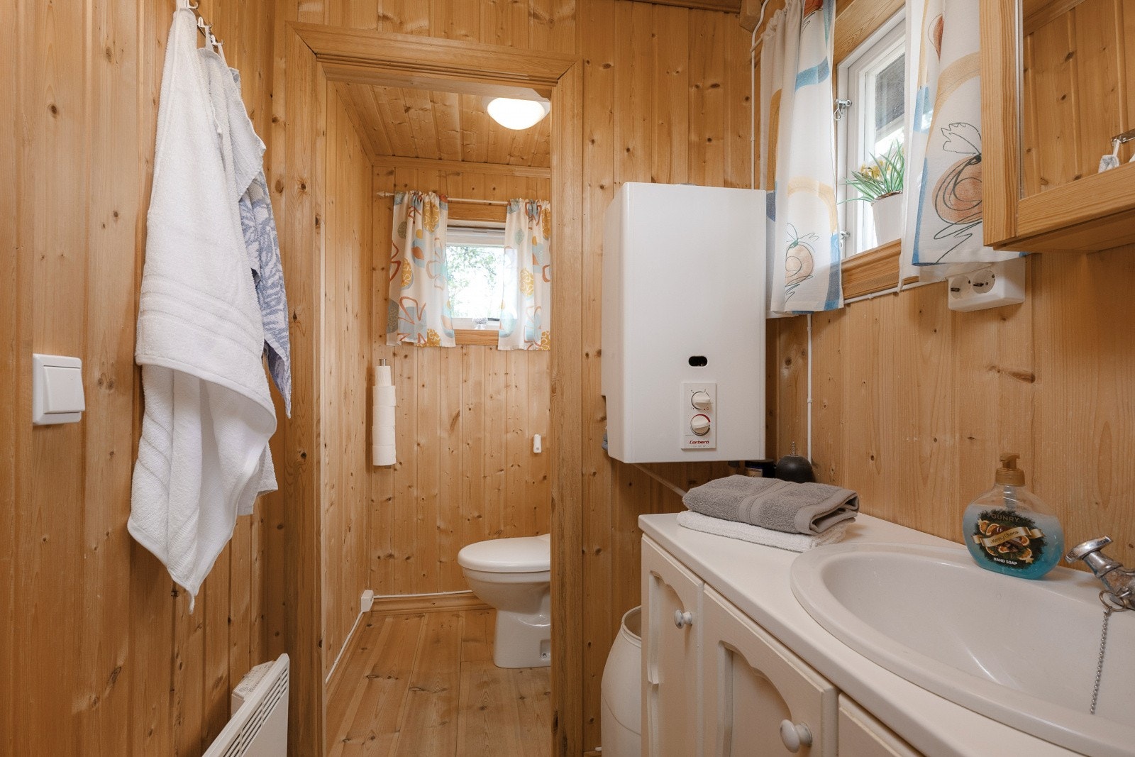 Badet utstyrt med enbaderomsinnredning, et gulvmontert Jets-toalett, montert i 2023, samt et dusjområde som delvis er trukket inn i bodrommet. Galleribilde