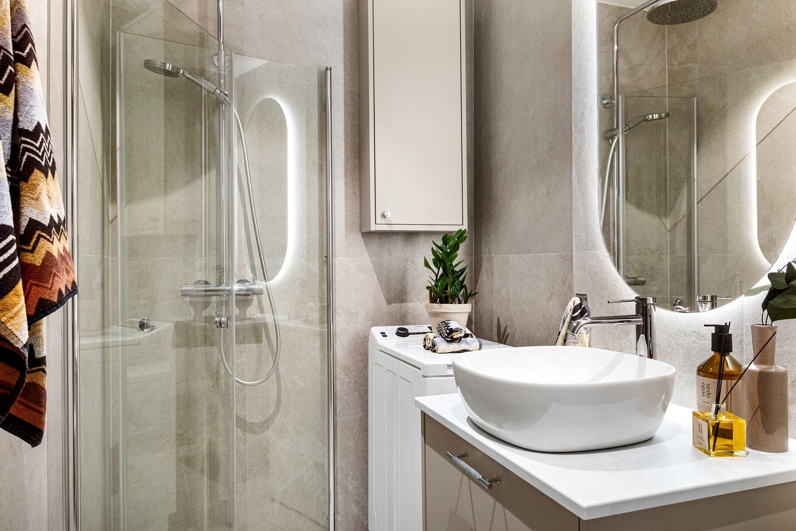 Baderommet er innredet med vegghengt toalett, servantskap, speil og dusjhjørne med svingdører. Galleribilde