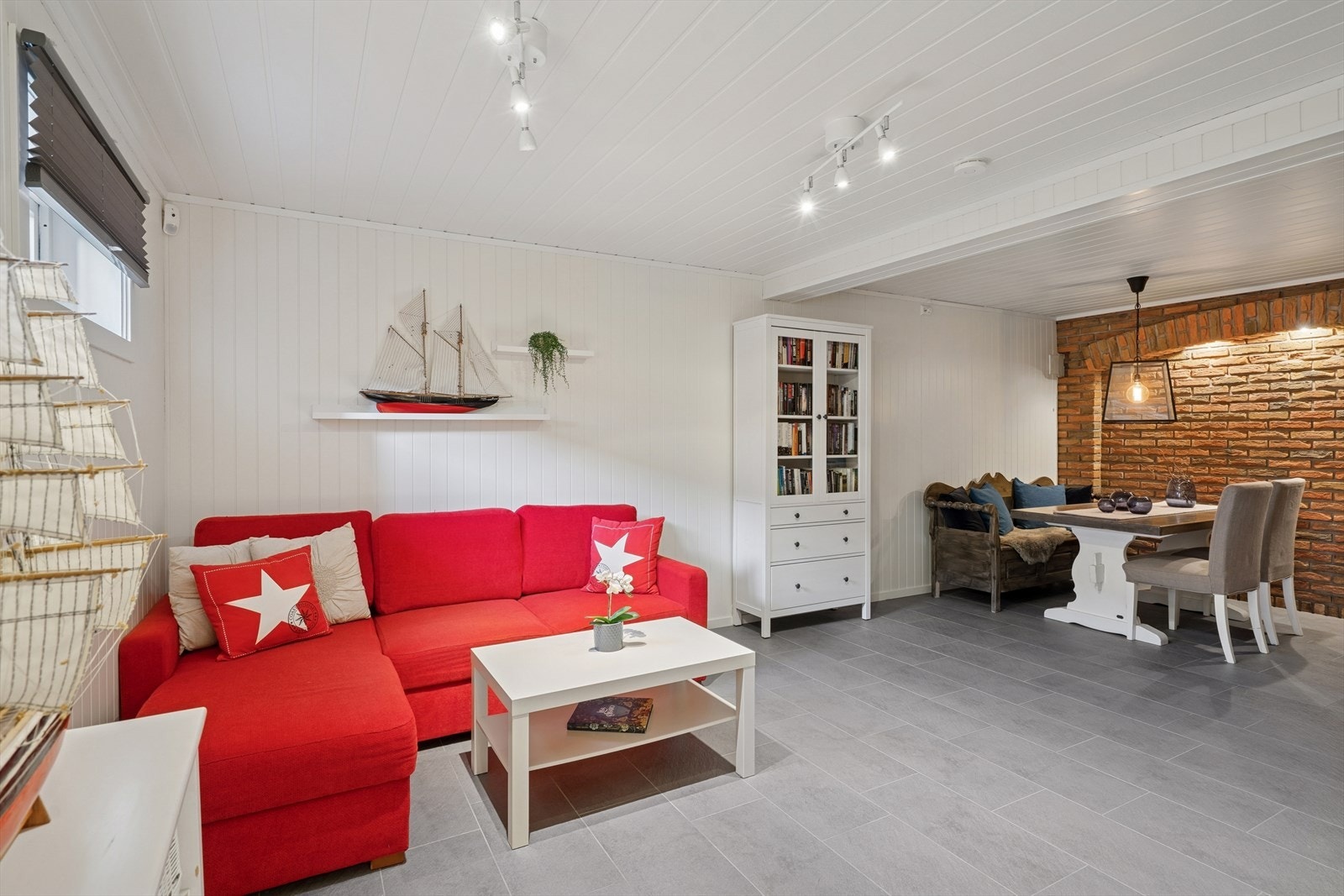 Stor og koselig stue med sofakrok og bord med sitteplasser ved peisen som skaper en varm og innbydende atmosfære Galleribilde