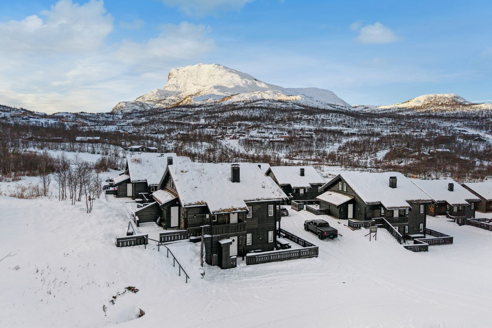 Yttervegger er oppført i tradisjonelt bindingsverk med liggende villmarkspanel, som gir bygningen et solid og rustikt utseende. Overbygget veranda med rekkverk i stående villmarkspanel og impregnert topplist gir ekstra uteplass og beskyttelse mot vær. Galleribilde