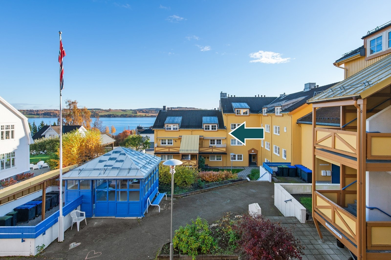 Felles tomteareal i bakgården. Tomten er opparbeidet med plen, beplantning og beplantet skråninger. Det er trapper i terrenget, forstøtningsmurer og hellebelagt. Lysthus/grillhytte og lekestue. Galleribilde