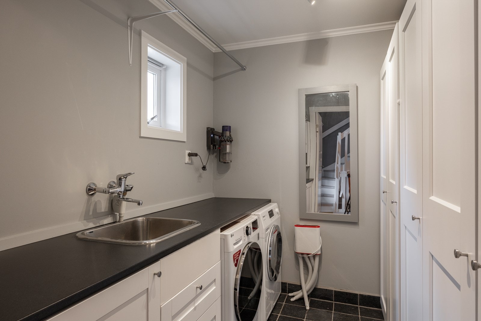 På samme plan finnes også et separat vaskerom med flislagt gulv og sluk, utslagsvask, opplegg for vaskemaskin og tørketrommel samt god benkeplass og skapoppbevaring, praktisk plassert i nærheten av inngangspartiet. Galleribilde