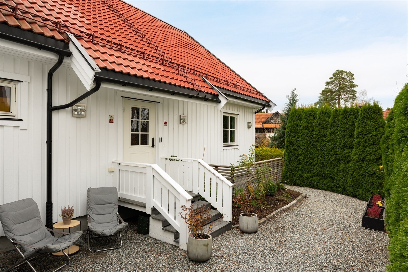 Tomten er pent opparbeidet med beplantning, plen og grusbelagt innkjørsel. Galleribilde