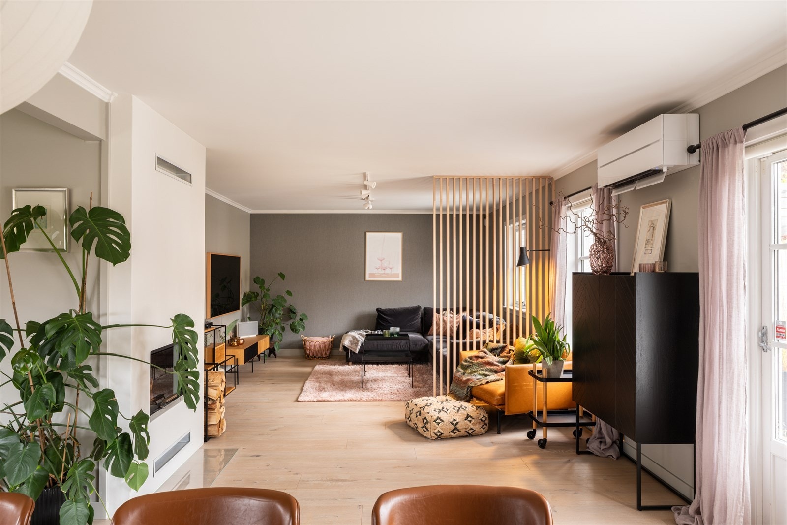 En elegant skillevegg med spiler markerer overgangen mellom stue og spisestue på en stilren måte, uten å stenge for lys og romfølelse. Galleribilde