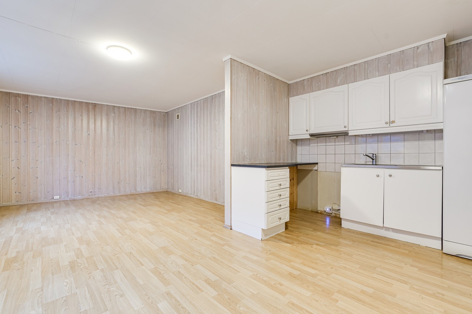 Lyse, glatte, folierte fronter til benkeskap med overliggende rustfritt benkebeslag med integrert. Galleribilde