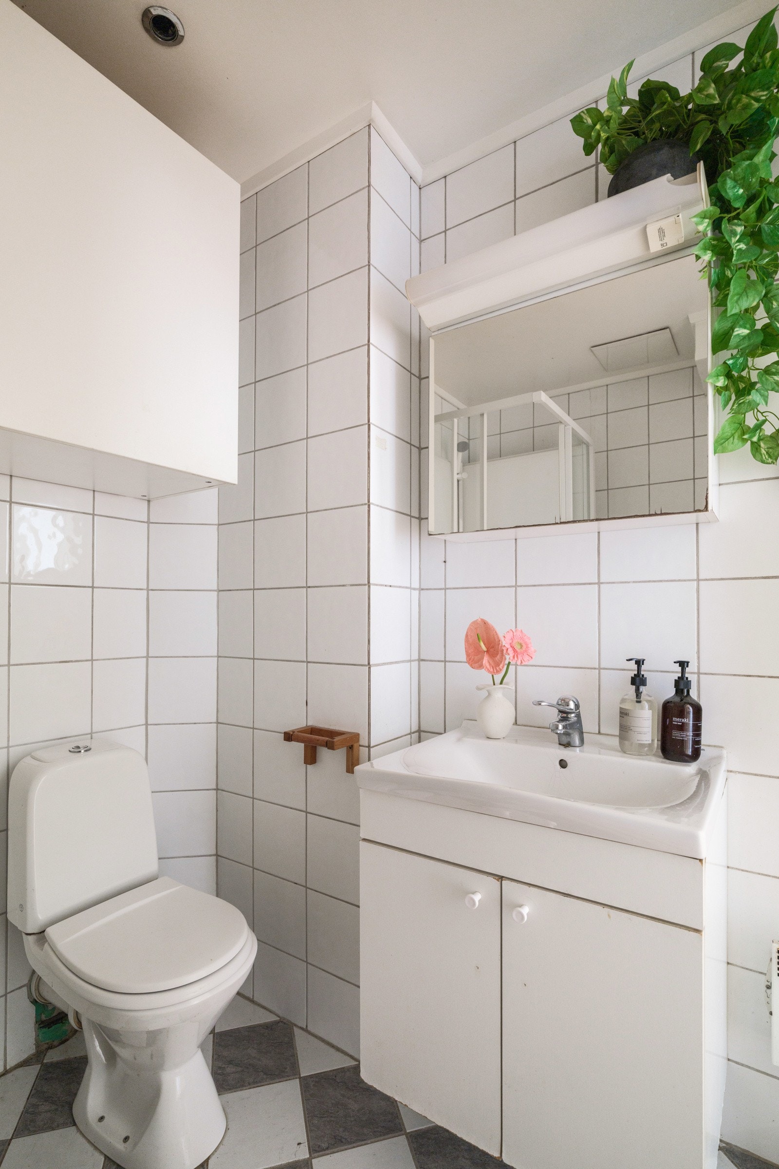 Baderommet har lyse fliser på gulv og vegger. Rommet er utstyrt med servantskap, speilskap med belysning over, dusjkabinett og gulvstående gulv. Galleribilde