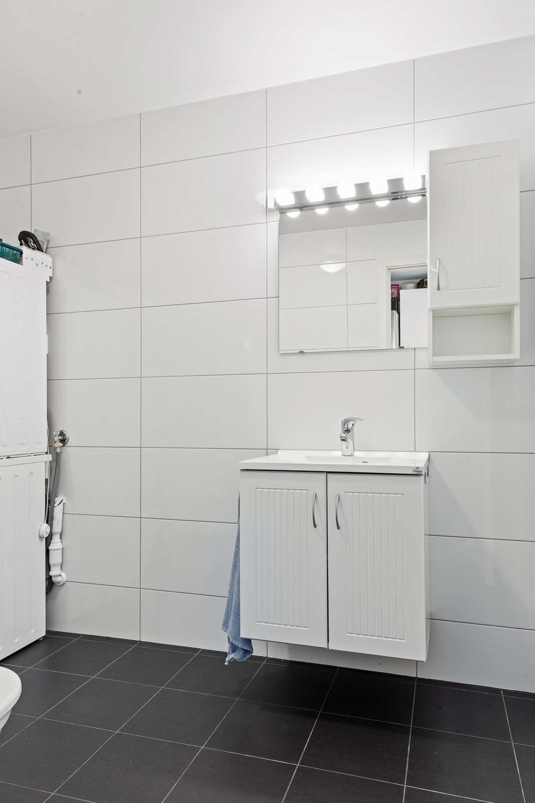 Flislagt bad med elektriske varmekabler i gulvet, servantinnredning, speil, belysning og sideskap. Galleribilde