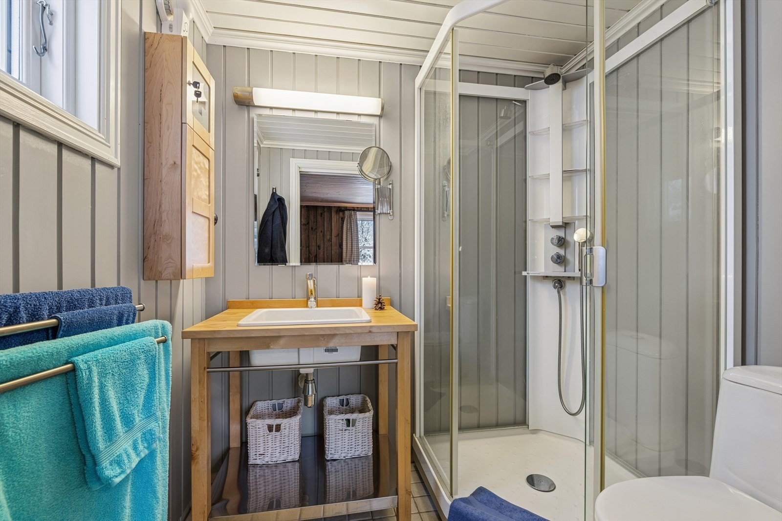 Baderommet har flislagt bad og panel på vegger. Badet er innredet med servant i møbel, toalett og dusjkabinett. Galleribilde