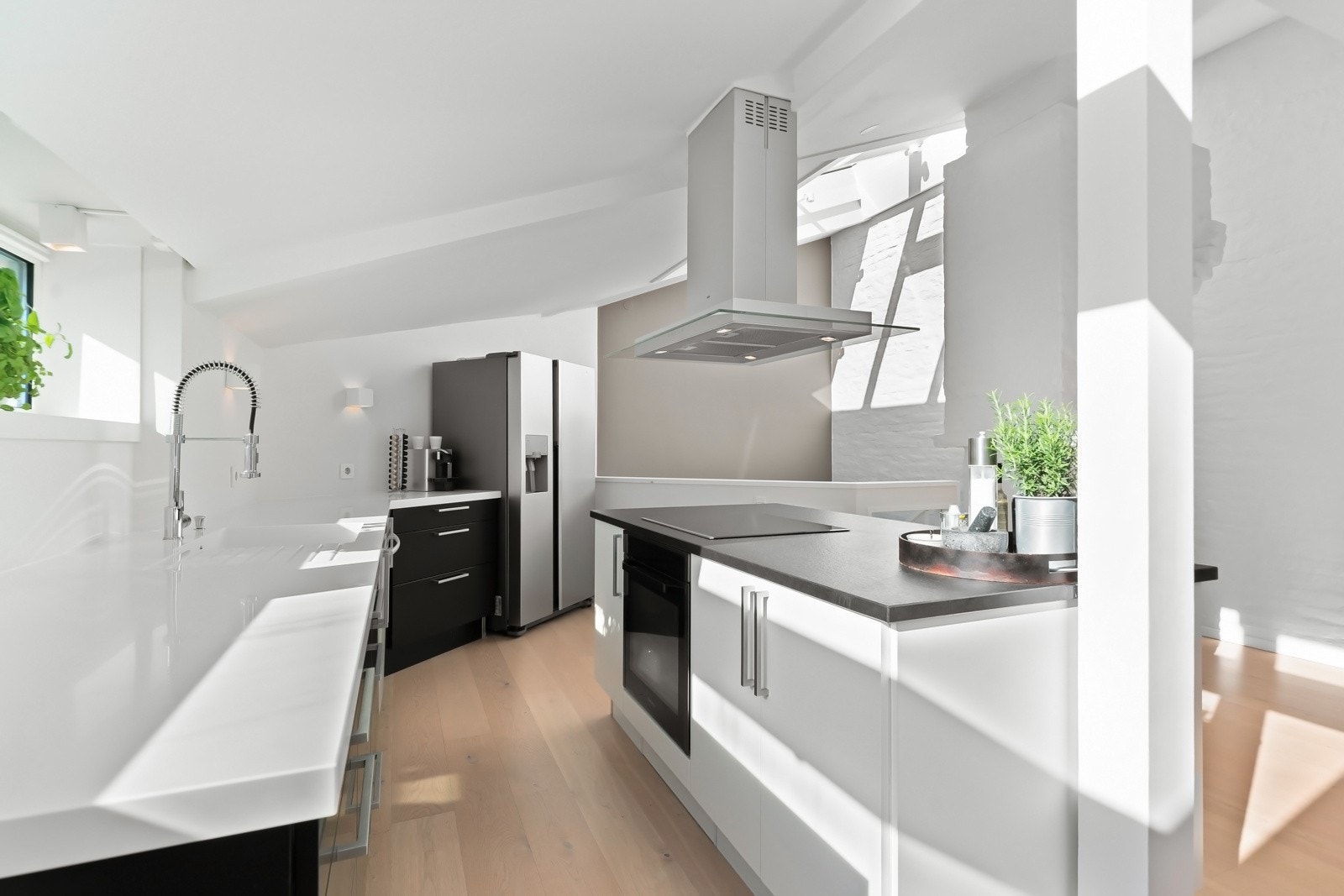 Hvitevarer som oppvaskmaskin, induksjonstopp og stekeovn, samt et frittstående side-by-side kjøleskap. Galleribilde