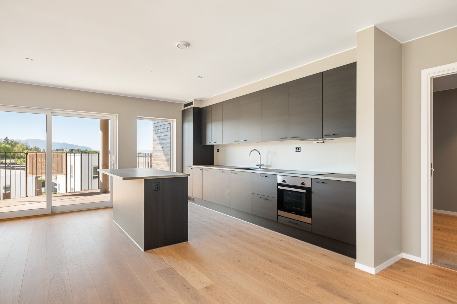 Stort kjøkken fra JKE design med høyskap, kjøkkenøy og mye skap- og benkeplass. Galleribilde