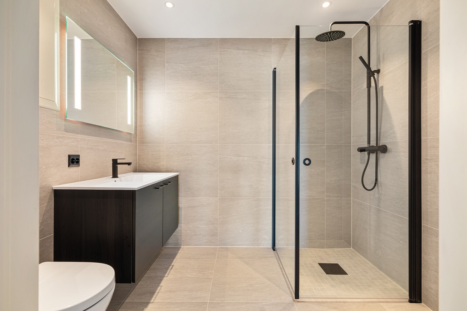 Moderne flislagt bad med 60x60 flis på gulv og vegger og mosaikkflis i dusj. Opplegg for vaskemaskin. Galleribilde