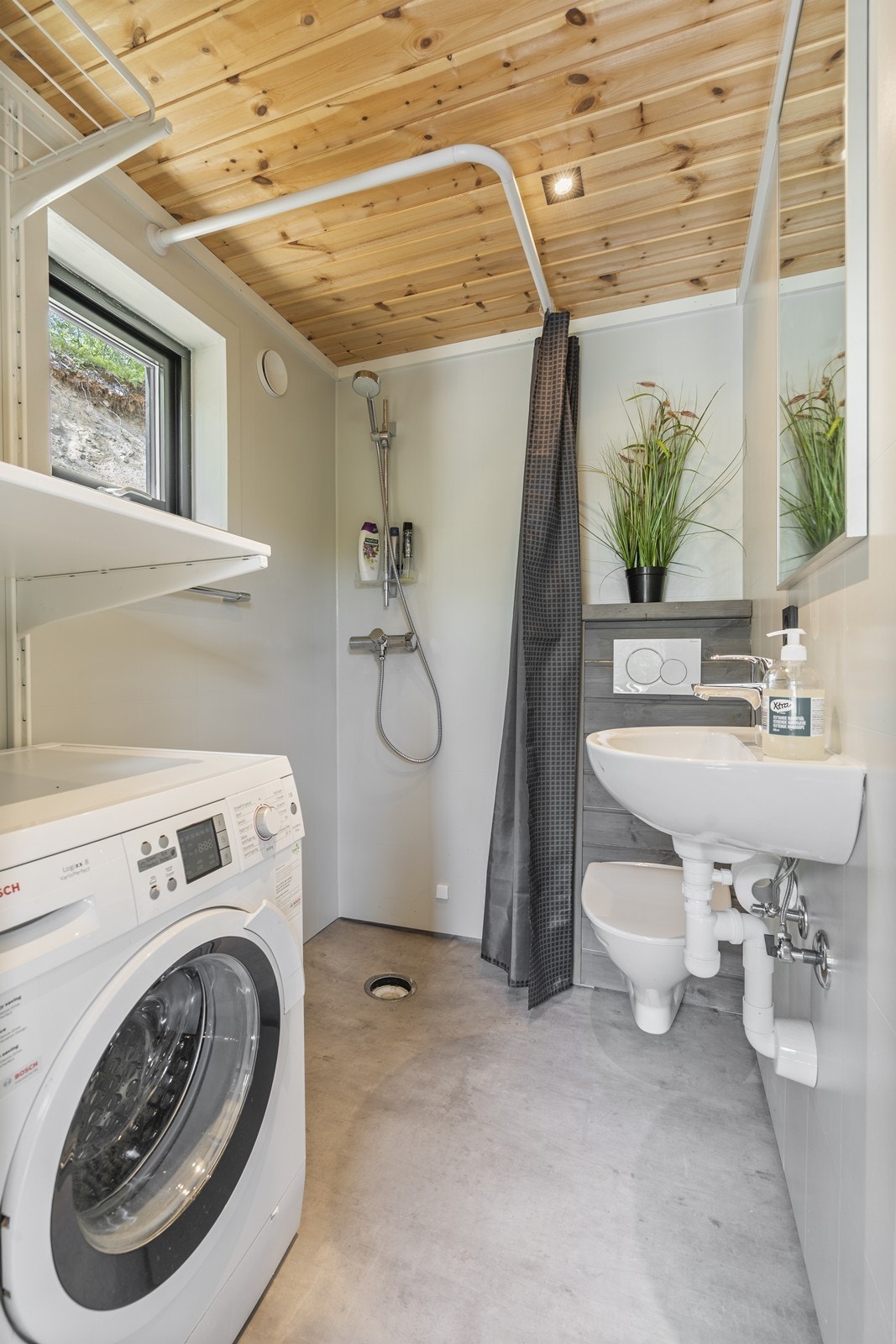 Funksjonelt baderom med dusj, opplegg for vaskemaskin og smart oppbevaringsplass. Galleribilde