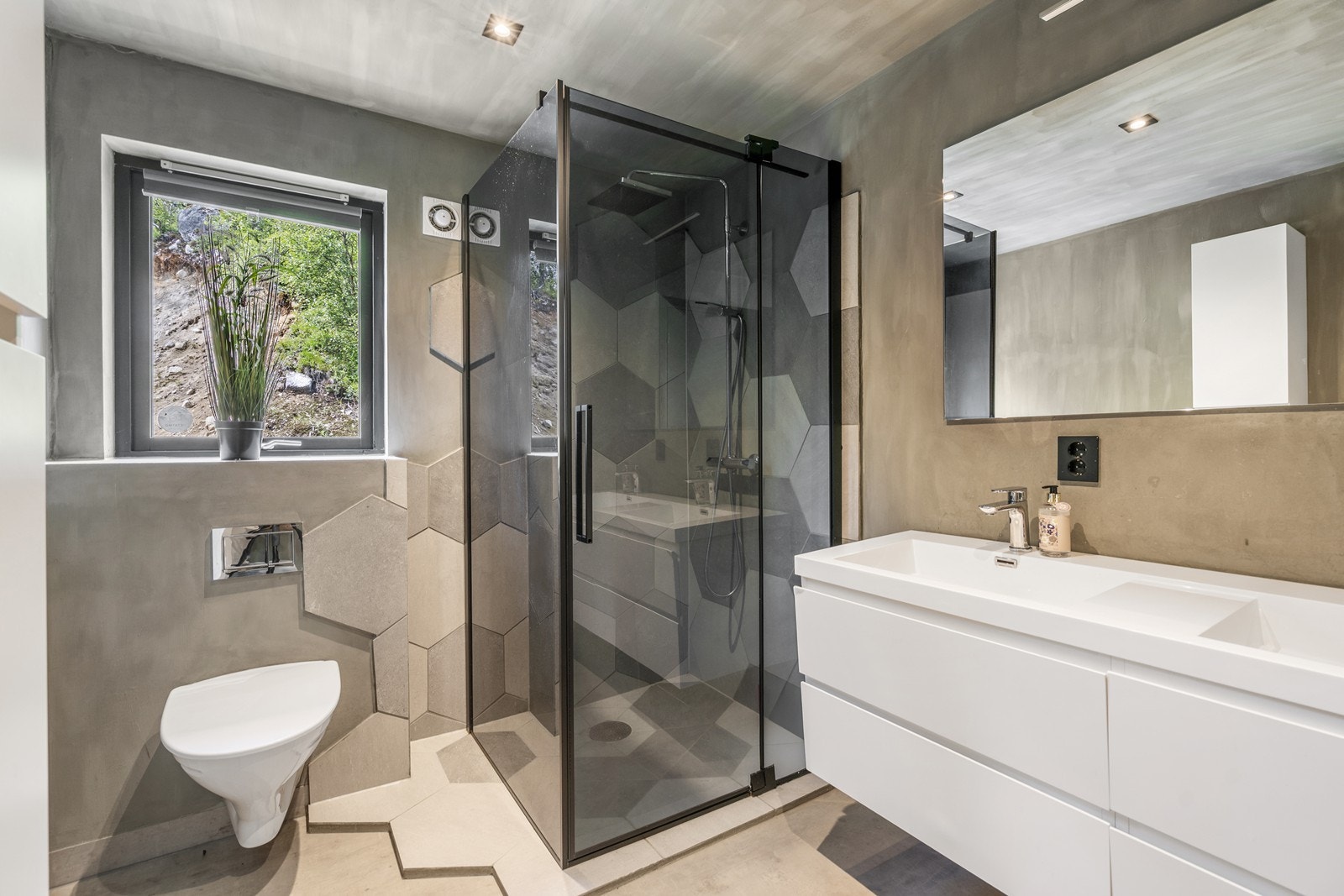 Stilrent baderom med hexagon-fliser i dusjsonen som gir rommet et ekstra særpreg. Galleribilde