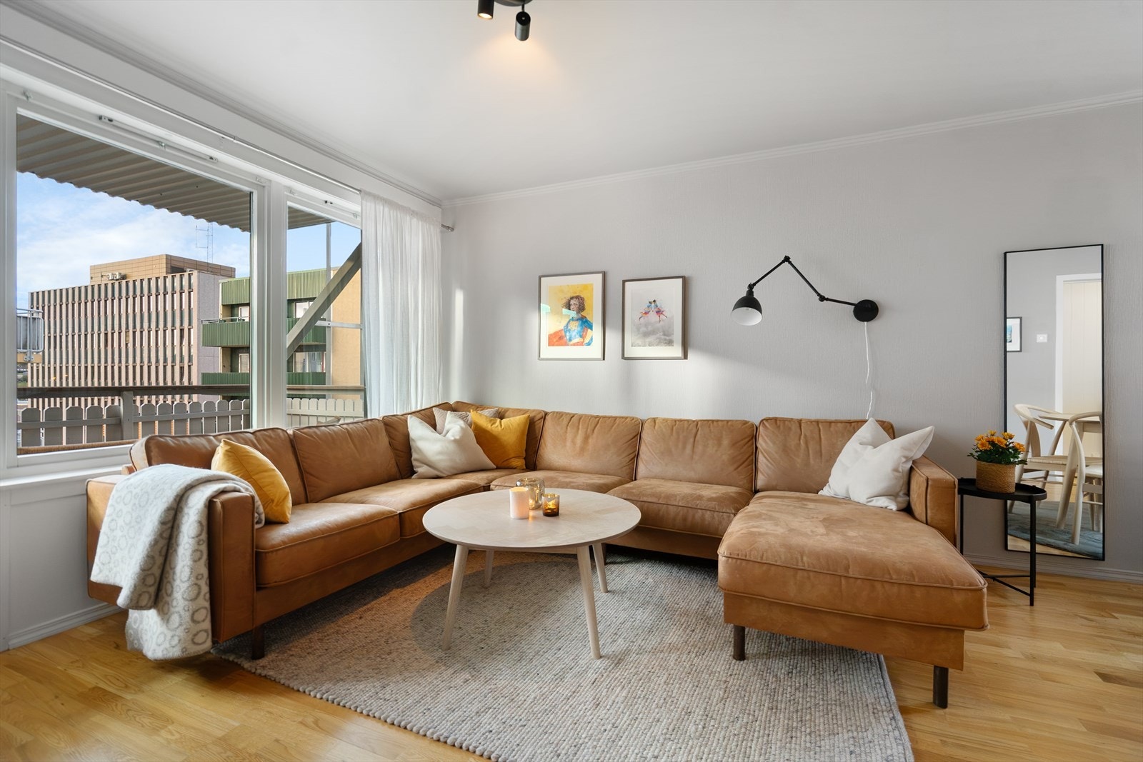 Sofasonen har en fin plassering mot store vinduer og utgang til balkongen - et herlig sted å nyte roen i hverdagen Galleribilde