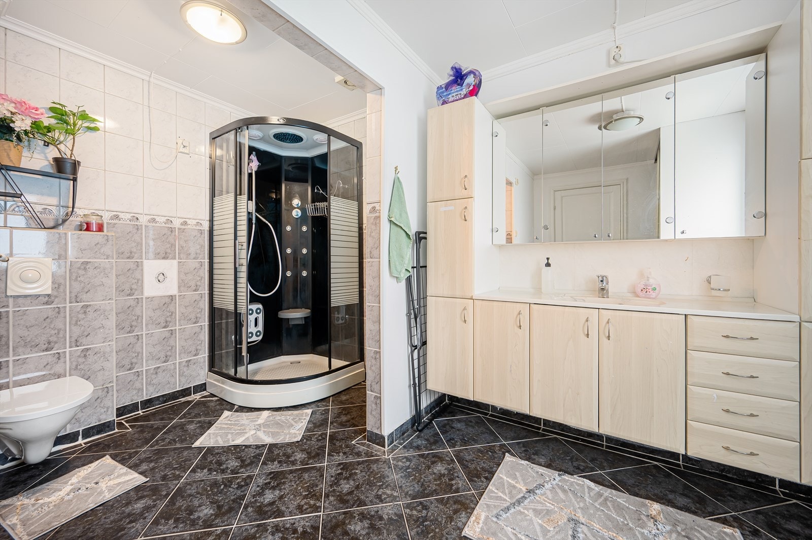 Badet er utført med fliser på gulvet, samt en kombinasjon av fliser og malte plater på veggene. Galleribilde