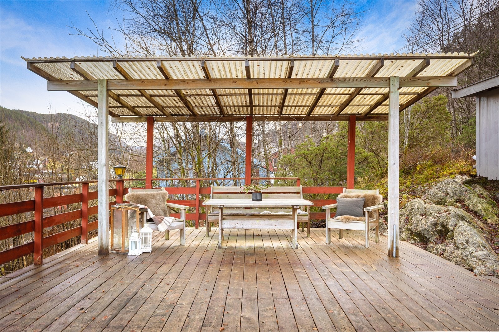 Tomten er opparbeidet med treterrasse og betongplatting på sørsiden av bygget. Galleribilde