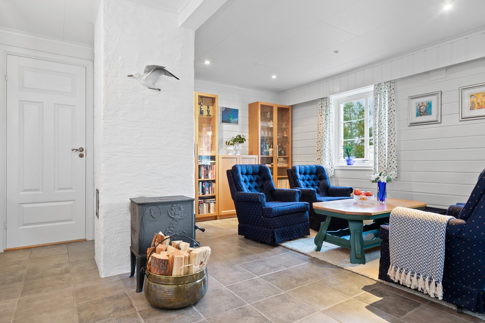 Kjellerstuen har hvitmalt panel på veggene, downlights i himlingen og lysegrå fliser på gulvet. Galleribilde