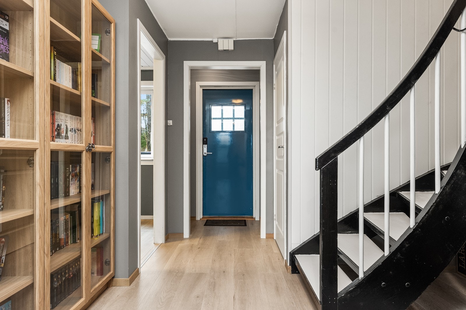 Lys entré med laminatgulv og en malt tretrapp som leder opp til andre etasje. Galleribilde