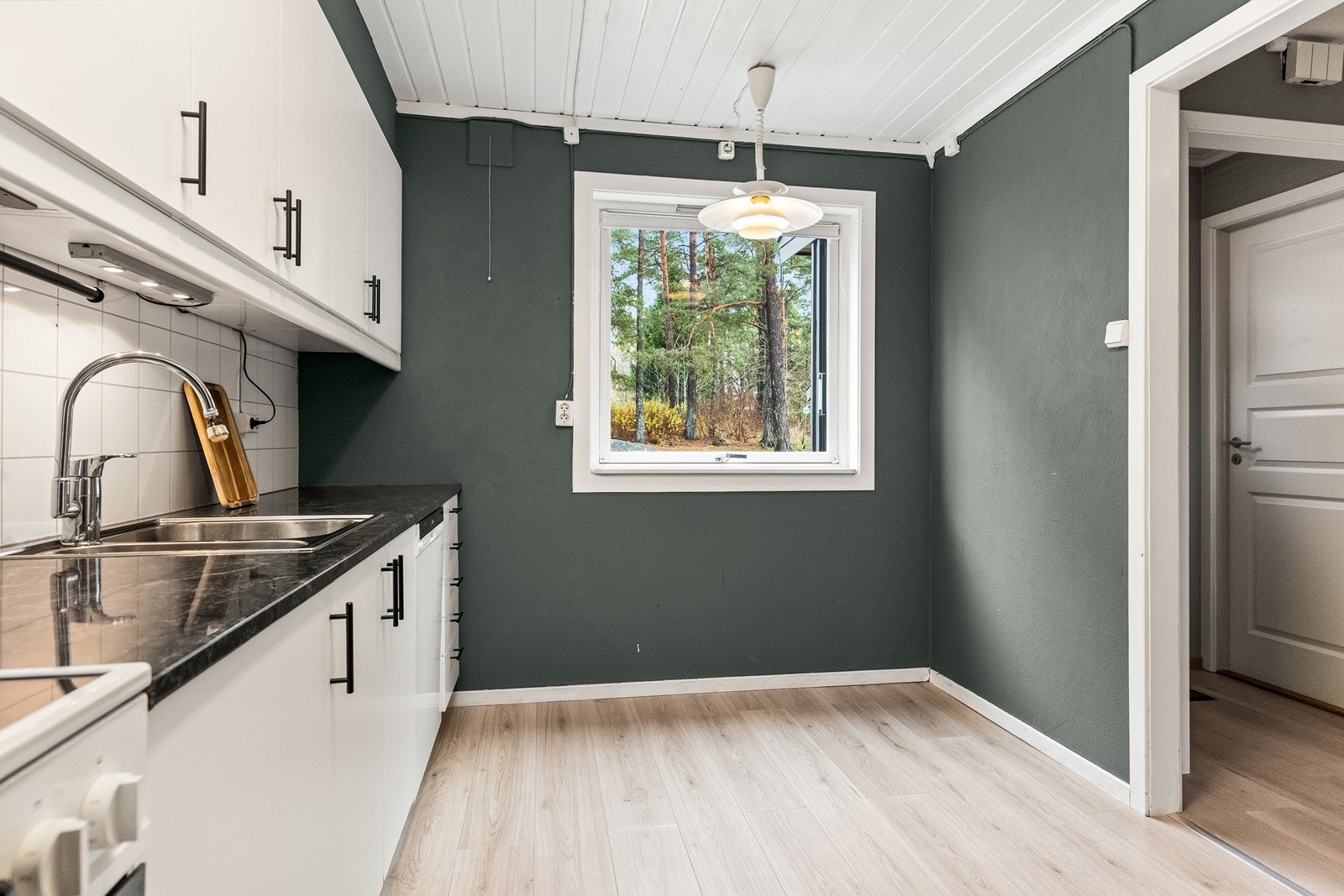 Kjøkkeninnredning med glatte fronter, laminatbenkeplate og plass til spisebord ved vinduet. Galleribilde