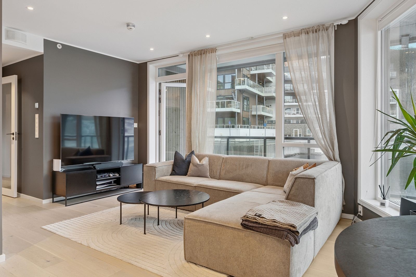 Romslig stue med moderne farger. Møblert med mellom annet sofa, spisebord og tv. Galleribilde