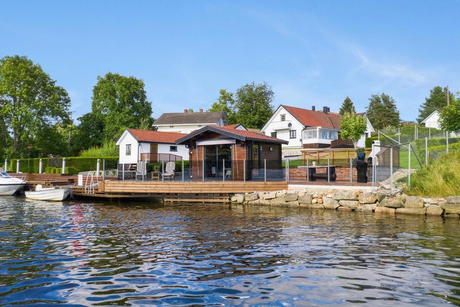 Tomten er pent opparbeidet med gressplen, diverse beplantning, kantstein, samt asfaltert innkjørsel/gårdsplass - Det er oppført brygge mot vannet, denne ligger utenfor eiendommens areal. Galleribilde