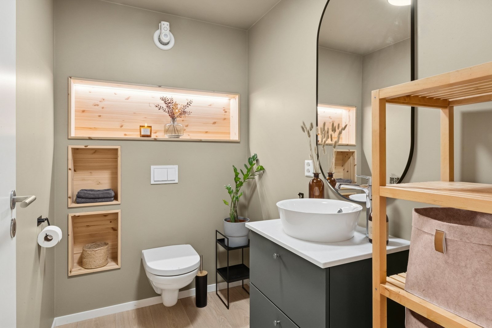 Boligen har også et separat toalettrom med et veggmontert toalett med innebygget sisterne, baderomsinnredning med toppmontert servant, speil og innebygde hyller. Galleribilde