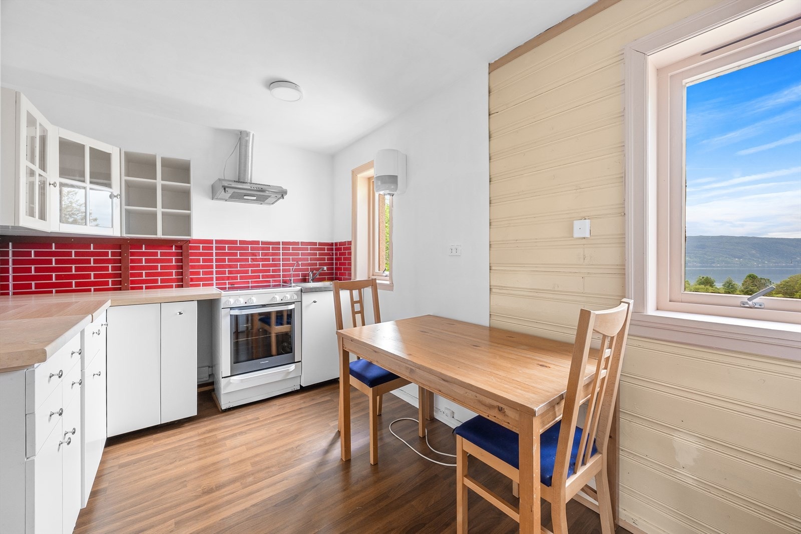 Lyst og romslig kjøkken på 9,8 m² med spiseplass og flere vindusflater som gir fin utsikt og mye lysinnslipp. Galleribilde