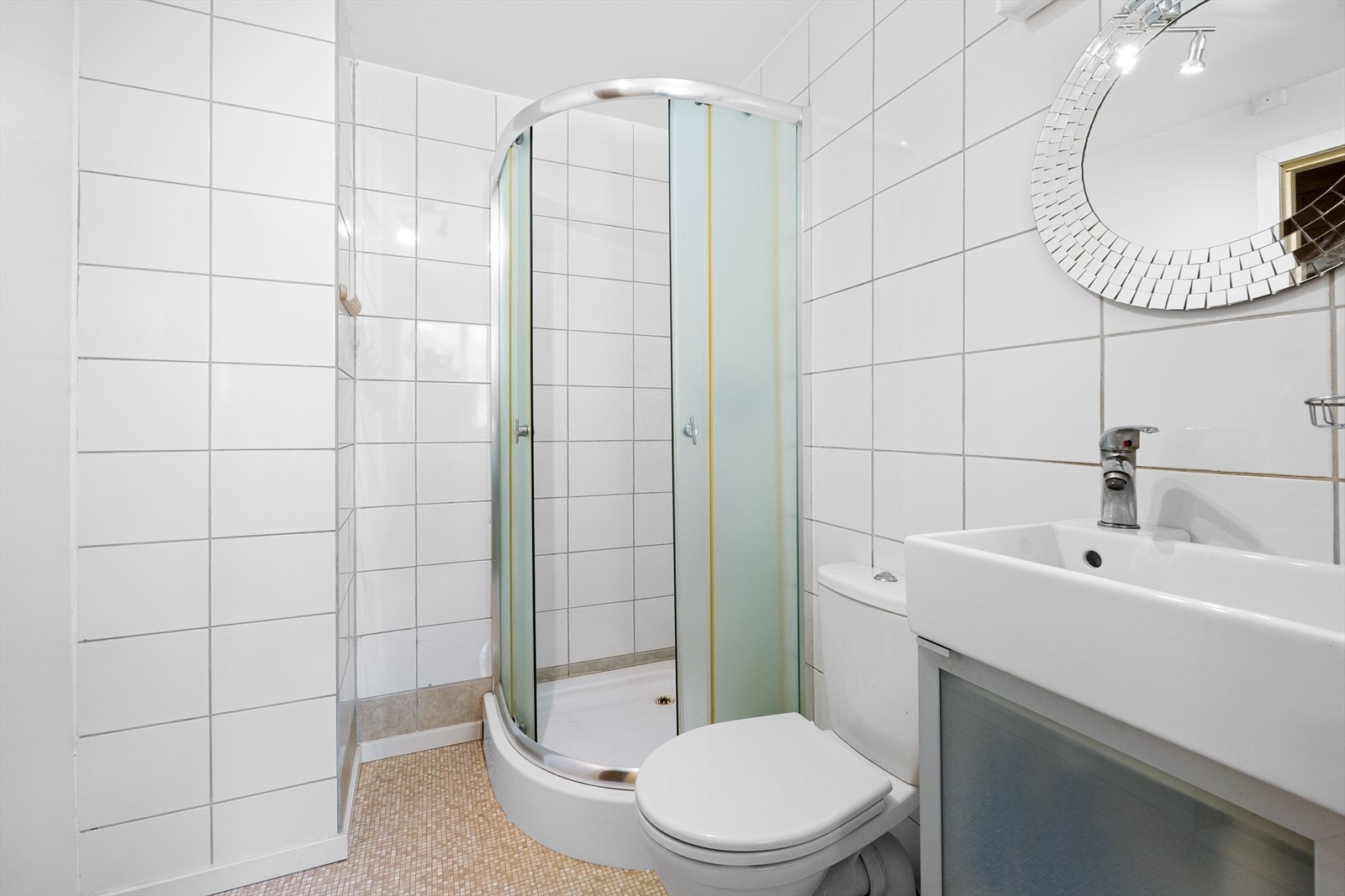 Badet er innredet med dusjhjørne, toalett og benkeskap med vask. Galleribilde