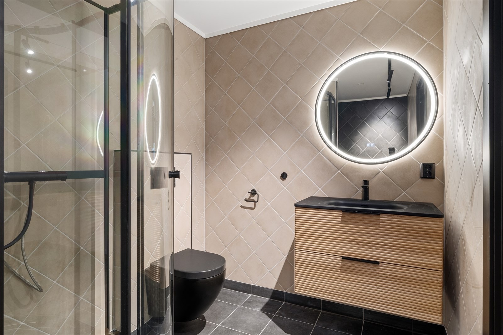 Rommet er praktisk innredet med dusjkabinett, servant med underskap og speil, samt vegghengt toalett som gir en luftig og elegant følelse. Galleribilde