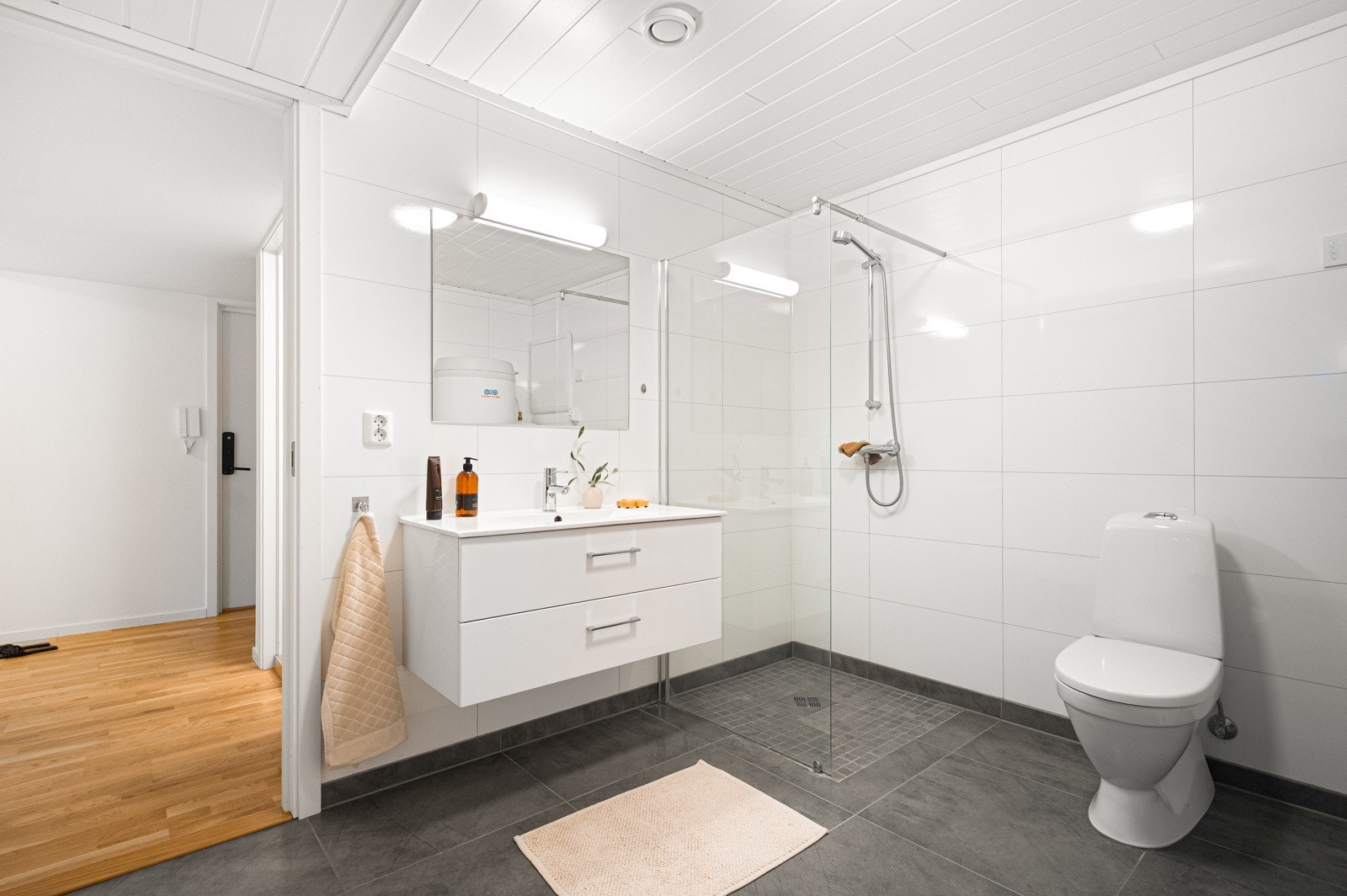 Leiligheten har to lyse baderom, som begge er innredet med dusj, toalett og servant med skuffeseksjon. Det største badet fungerer også som vaskerom og teknisk rom, med opplegg og plass til vaskemaskin og tørketrommel. Galleribilde