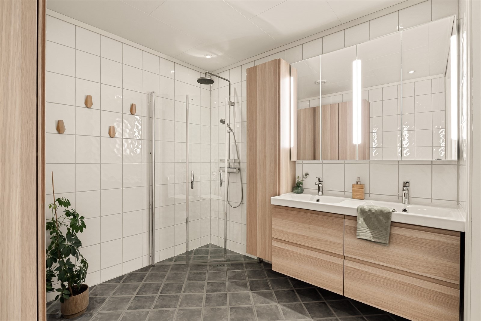 Hovedbadet i 1. etasje er romslig og smakfullt innredet, med fliser på både gulv og vegger samt behagelige, elektriske varmekabler. Galleribilde