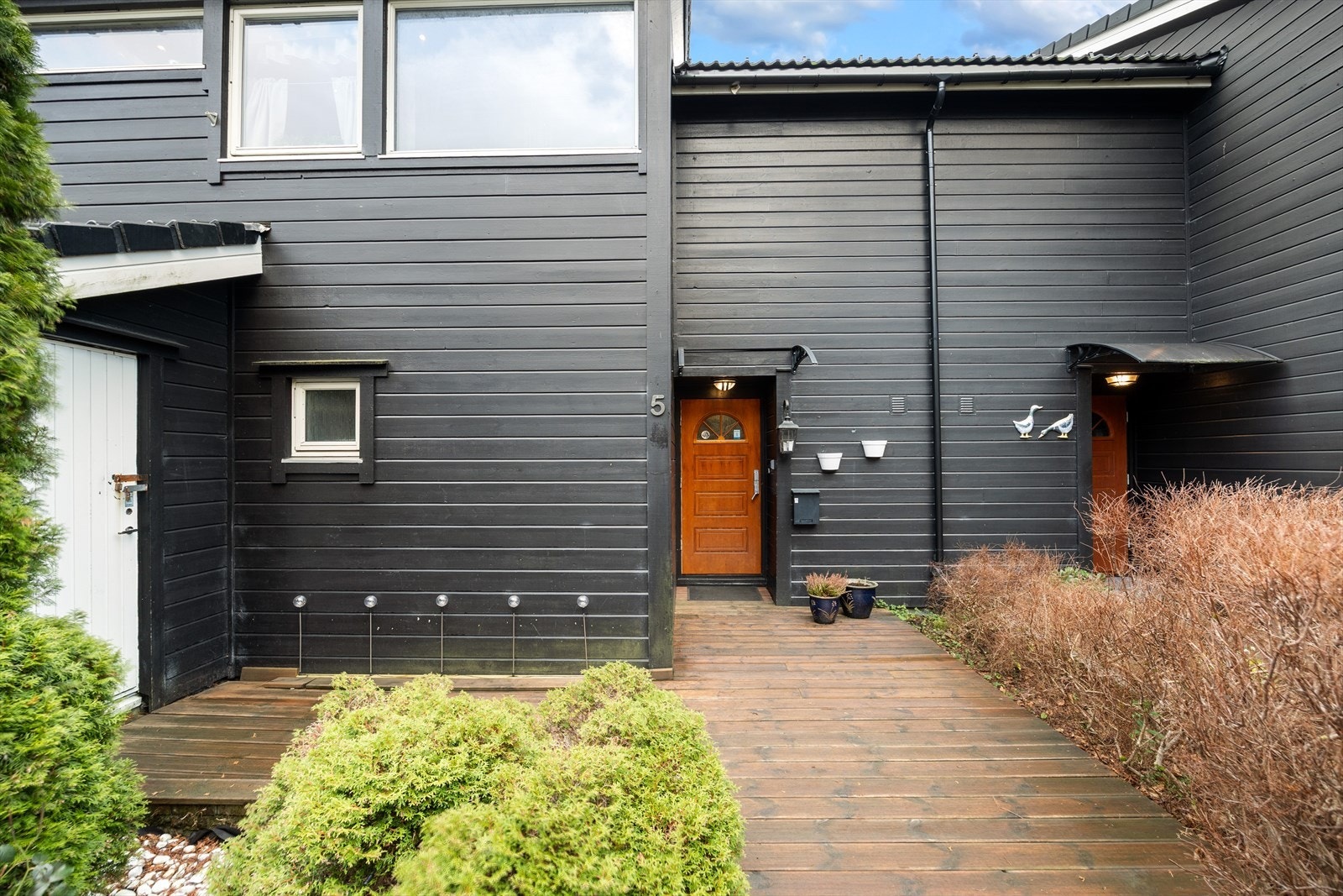 På boligens fremside er det tilkomst til en sportsbod og uteplass. Galleribilde