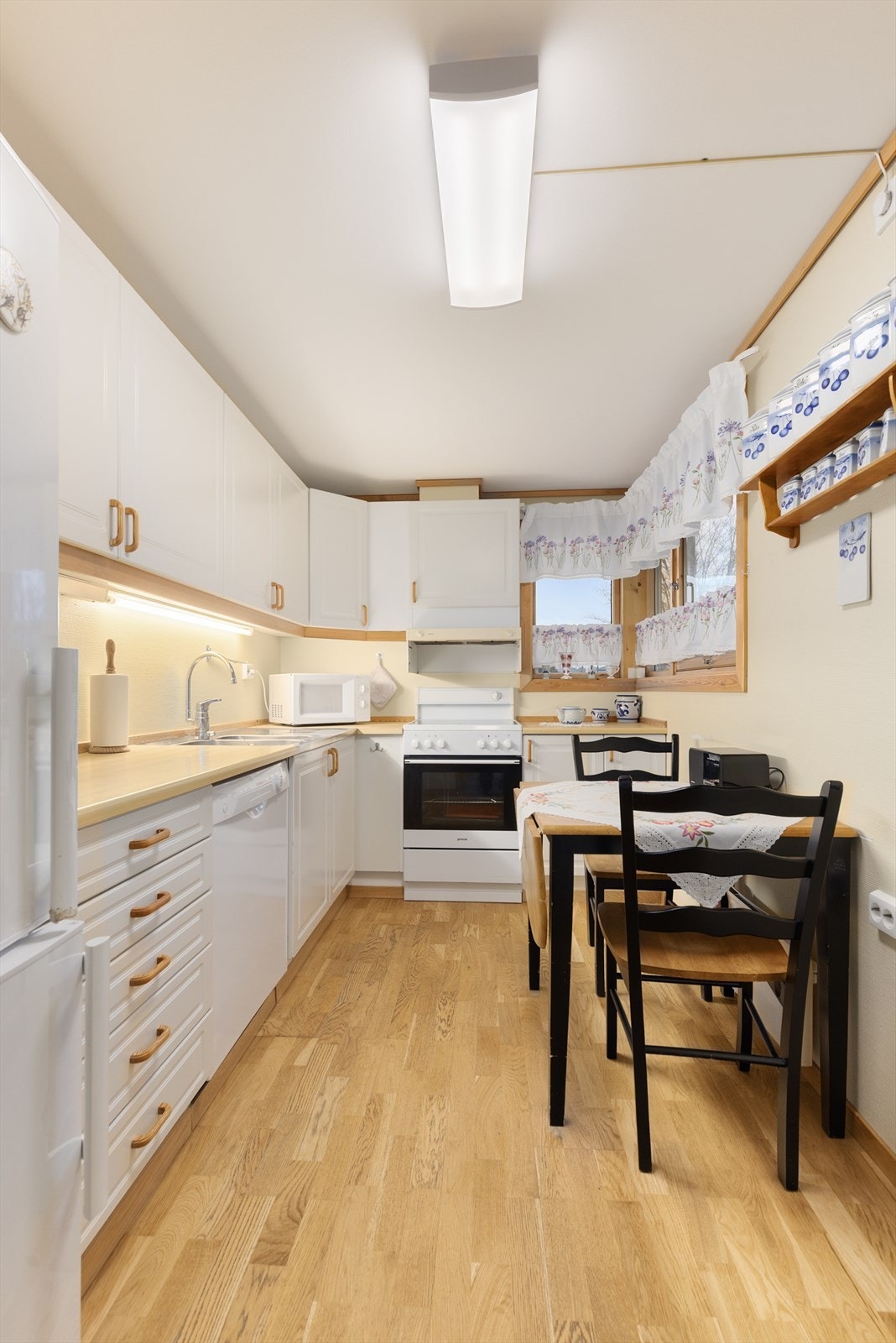 Lyst og trivelig kjøkken med plass til lite spisebord. Innredningen har profilerte fronter og laminert benkeplate. Galleribilde