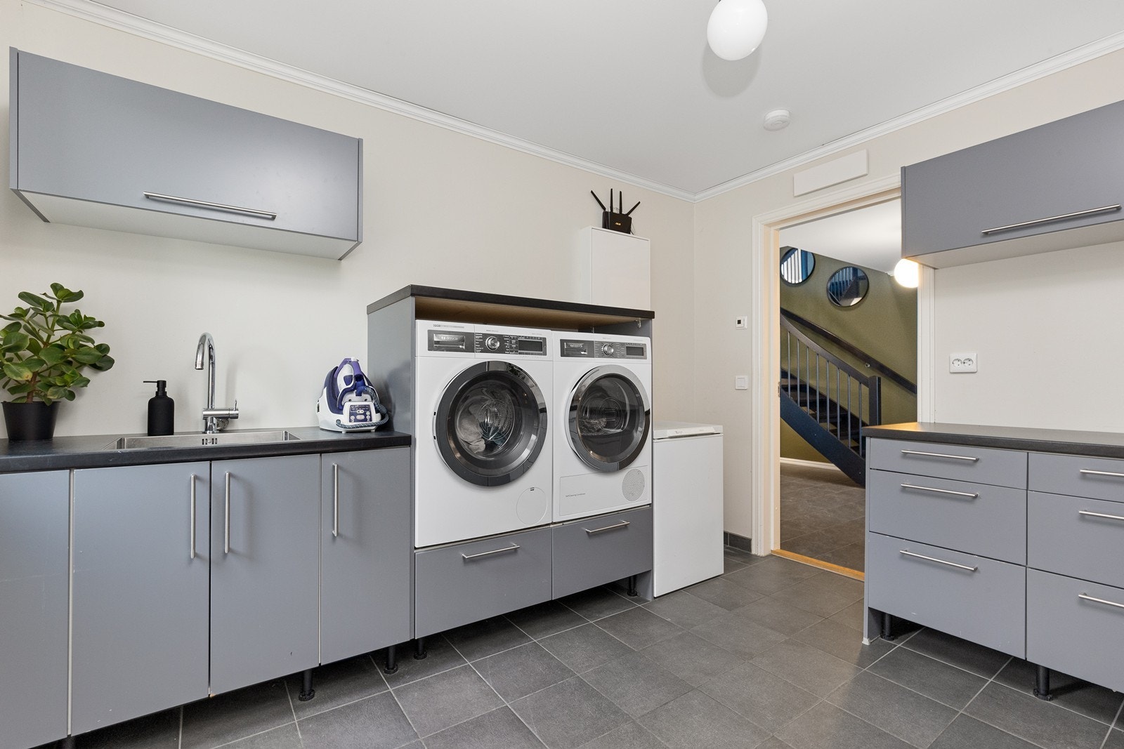 Praktisk vaskerom med flislagt gulv, varme i gulvet og god skap- og benkeplass Galleribilde