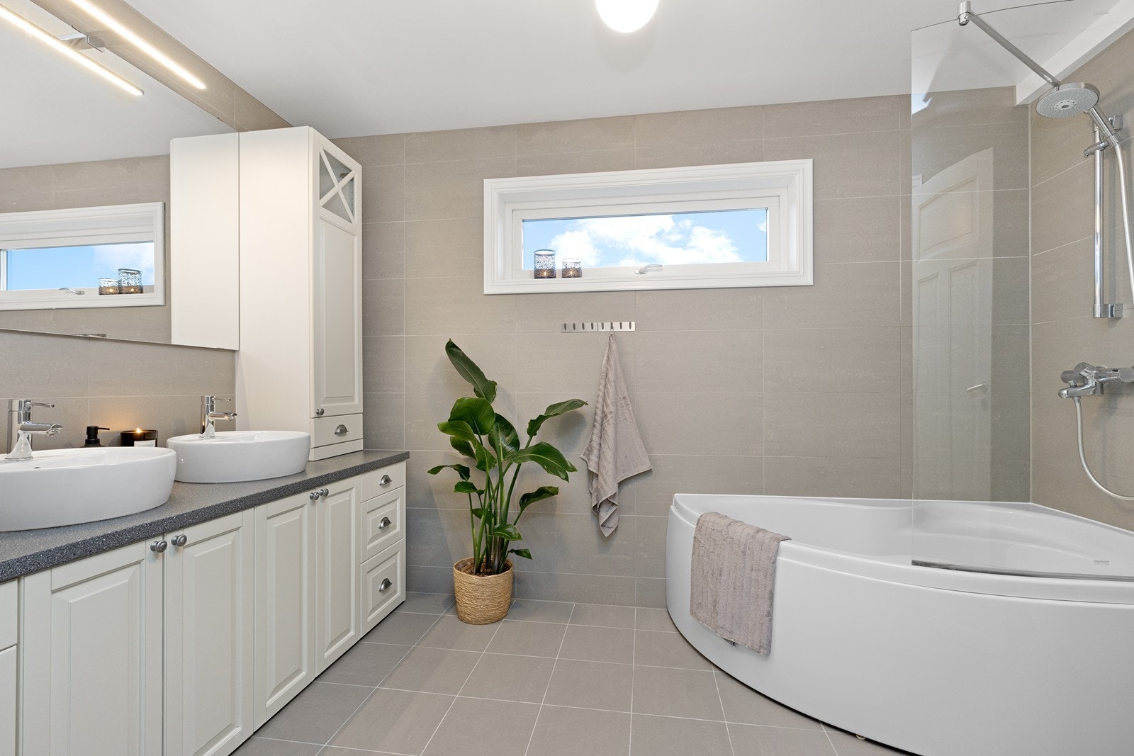 Hovedbadet er helfliset og utstyrt med et romslig hjørnebadekar Galleribilde