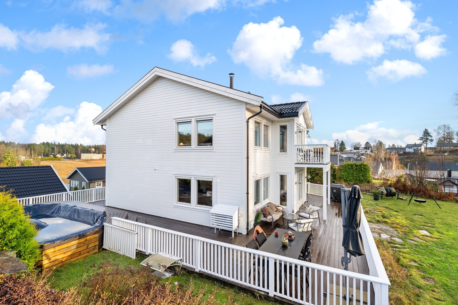 En nyere og romslig enebolig med en stor terrasse som strekker seg rundt store deler av huset Galleribilde