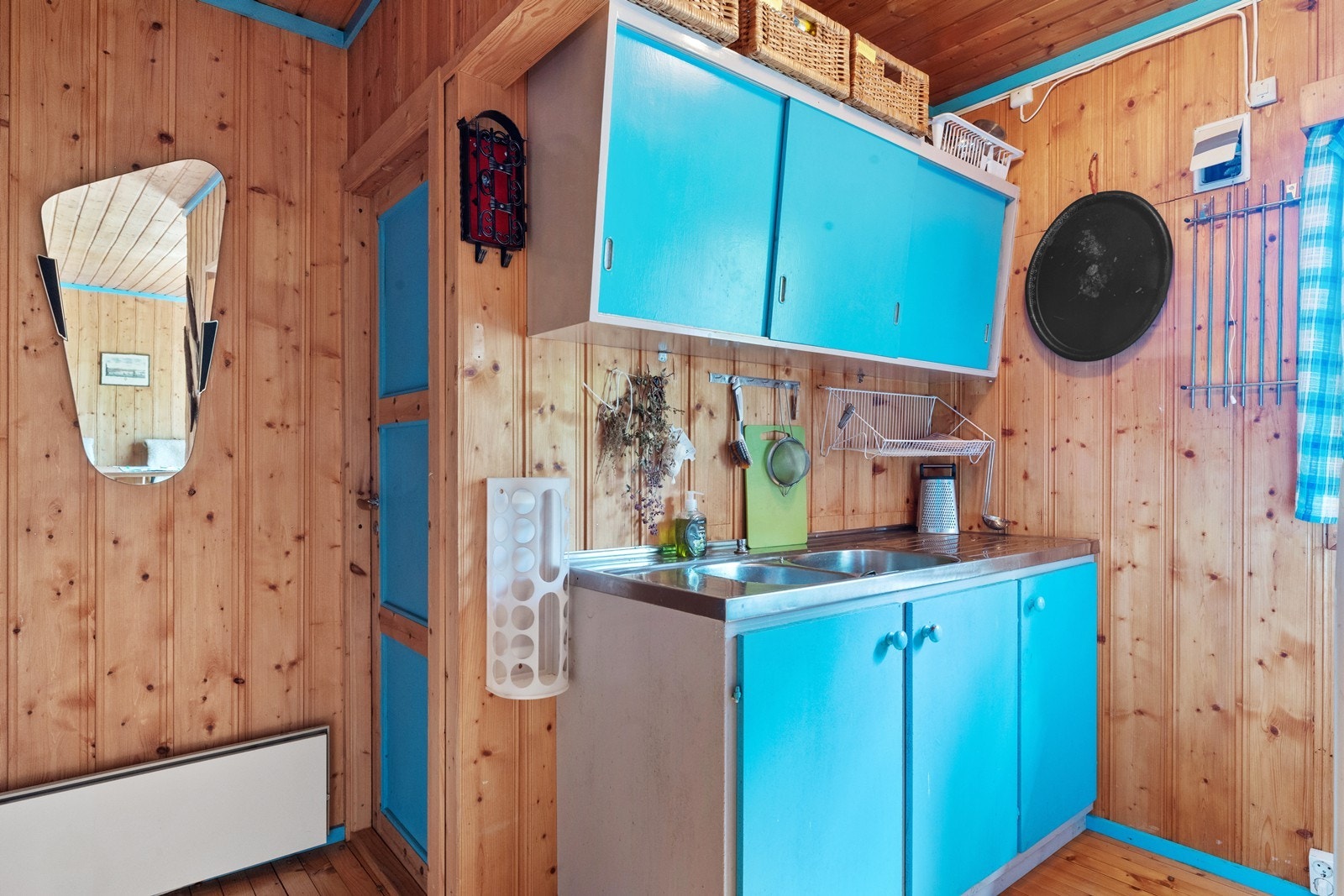 Kjøkkenet er trivelig og er av ukjent alder. Skapene er malt i en blå fargetone med glatte fronter og benkeplate av stål og laminat. Galleribilde