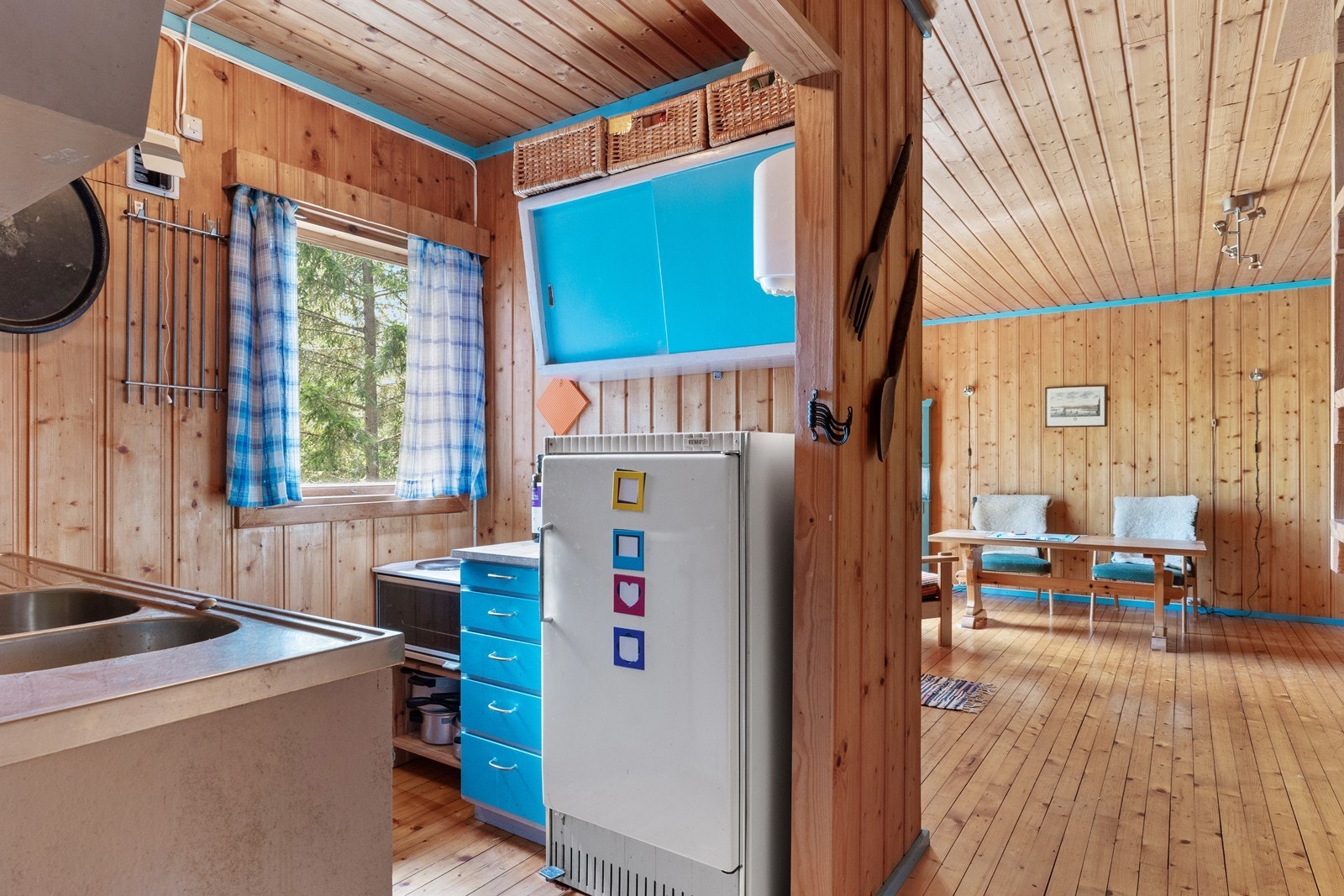 Rommet er enkelt innredet på to sider og har vindu som vender mot grønn natur. Hvitevarer består av frittstående komfyr og kjøleskap. Galleribilde