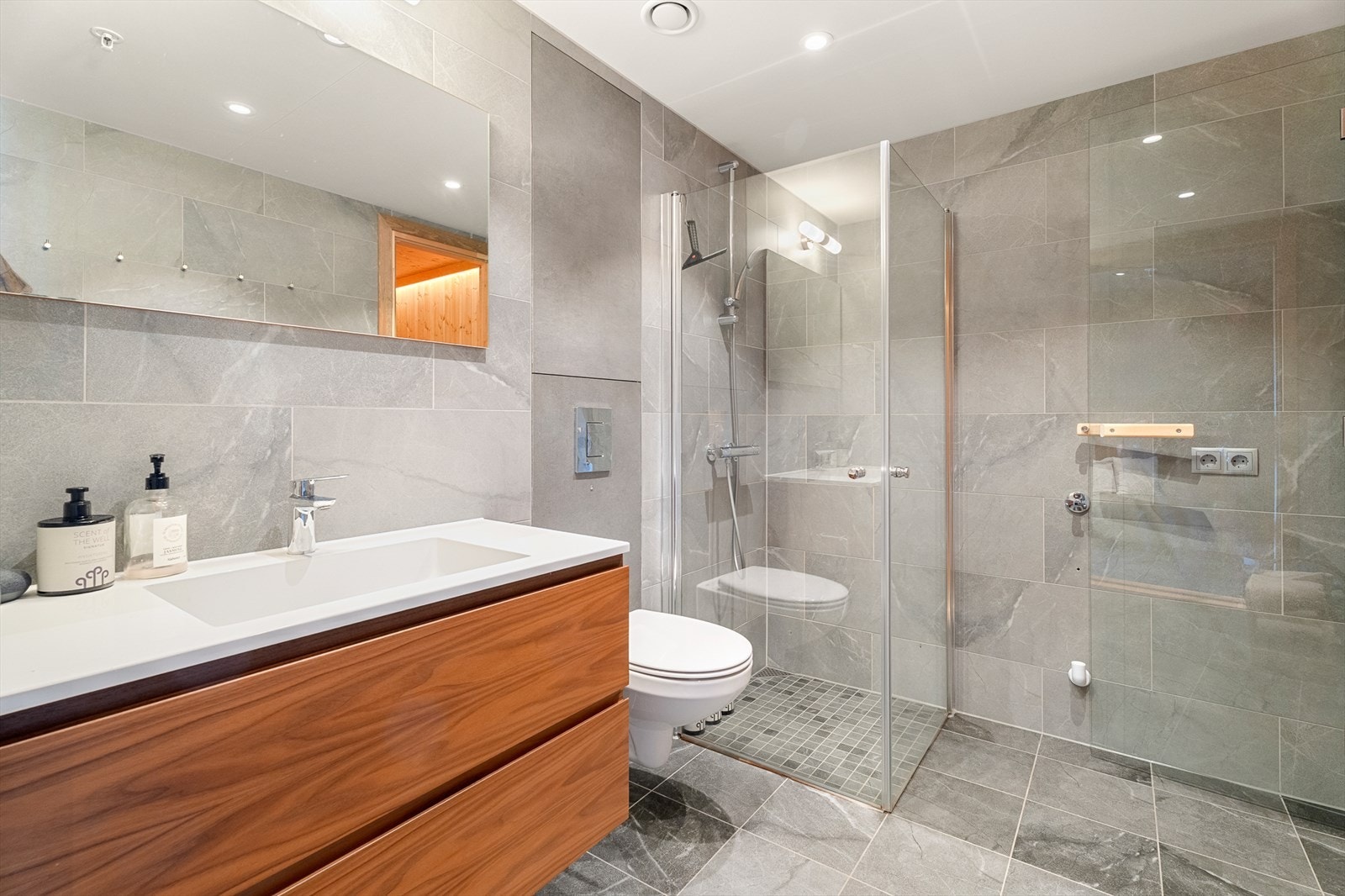 Moderne bad med fliser, gulvvarme, og en stilren innredning med stort servang, vegghengt toalett og dusjsone med herdet glass Galleribilde