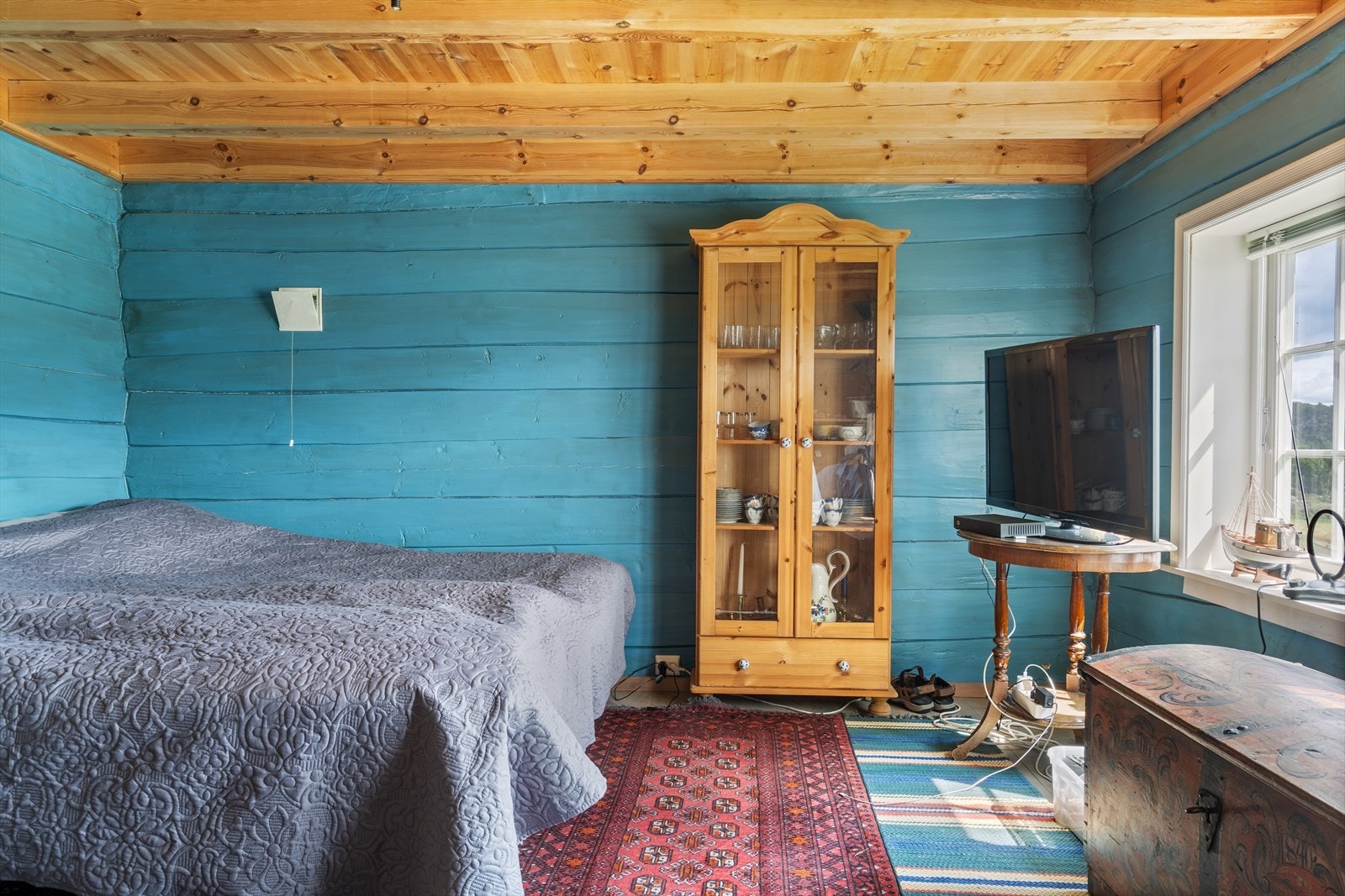 Et romslig soverom hvor de synlige takbjelkene og det gjennomgående fargevalget knytter rommet fint sammen med resten av huset. Galleribilde