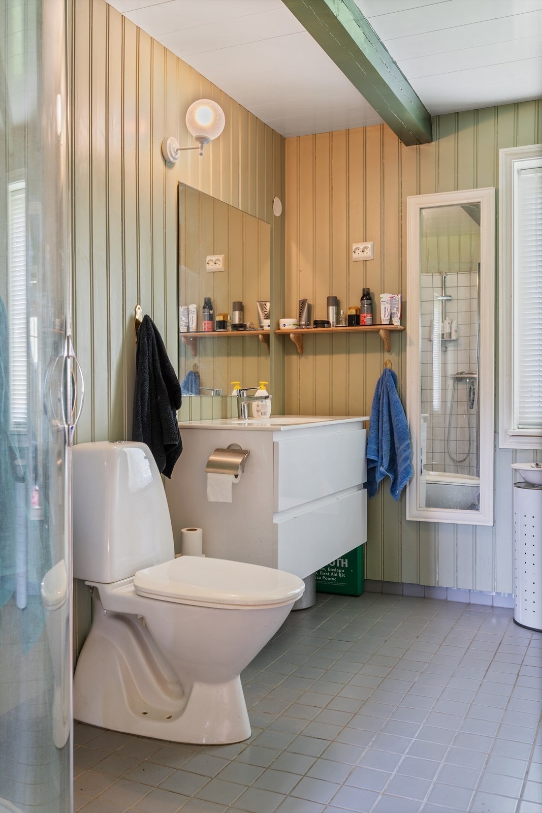 Fargevalget følger resten av huset, med malt panel på vegger og synlige takbjelker som knytter rommet til husets originale stil. Galleribilde