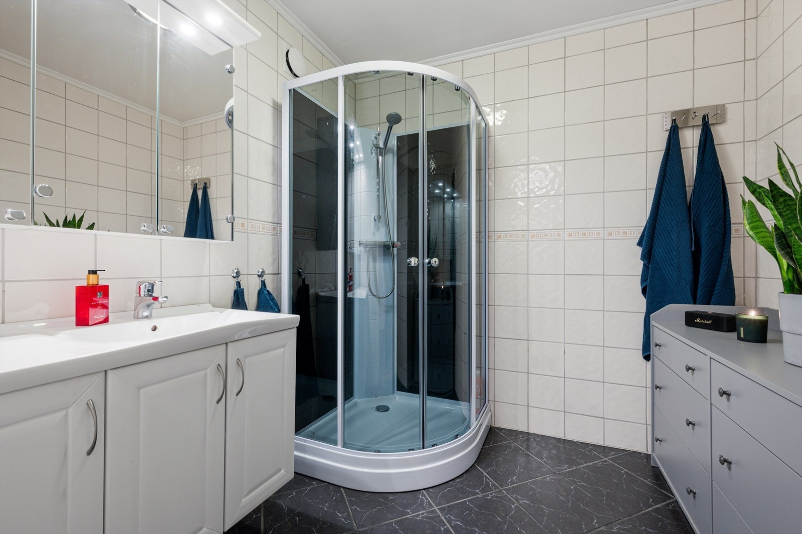 Delikat og flislagt baderom på hele 5,5m², utstyrt varme i gulv, nytt dusjkabinett fra 2025, naturlig avtrekk, servant og servantskap. Galleribilde