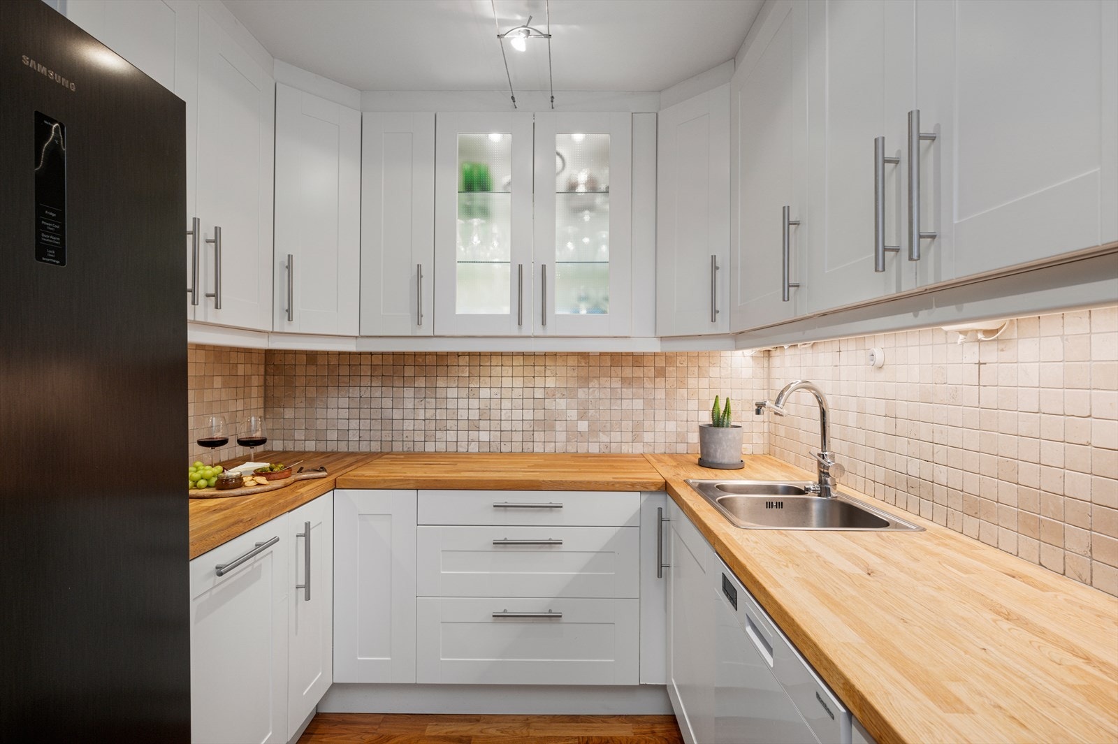 Kjøkkeninnredning med integrert platetopp, stekovn, opplegg for oppvaskmaskin og mekanisk avtrekksvifte over stekesonen. Galleribilde